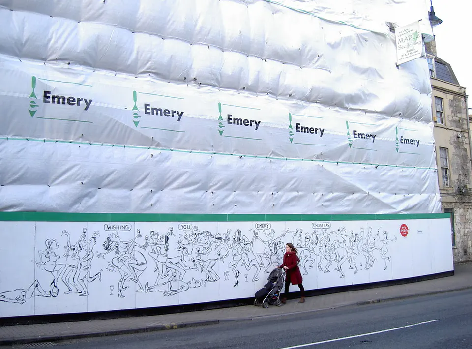 Bath stone building wrapped in scaffolding sheeting and hoarding