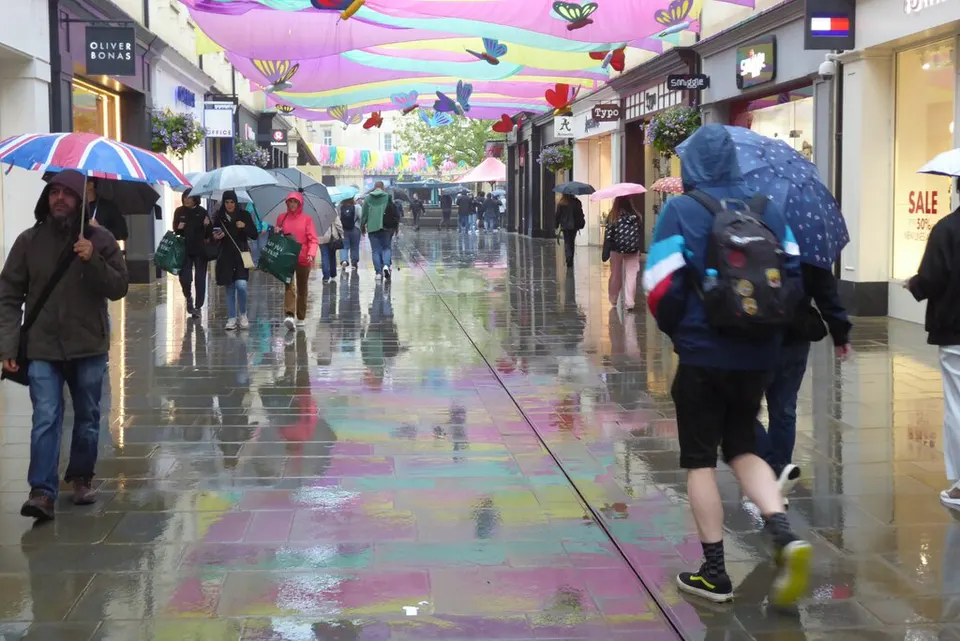 Shoppers with umbrellas in the rain in Bath