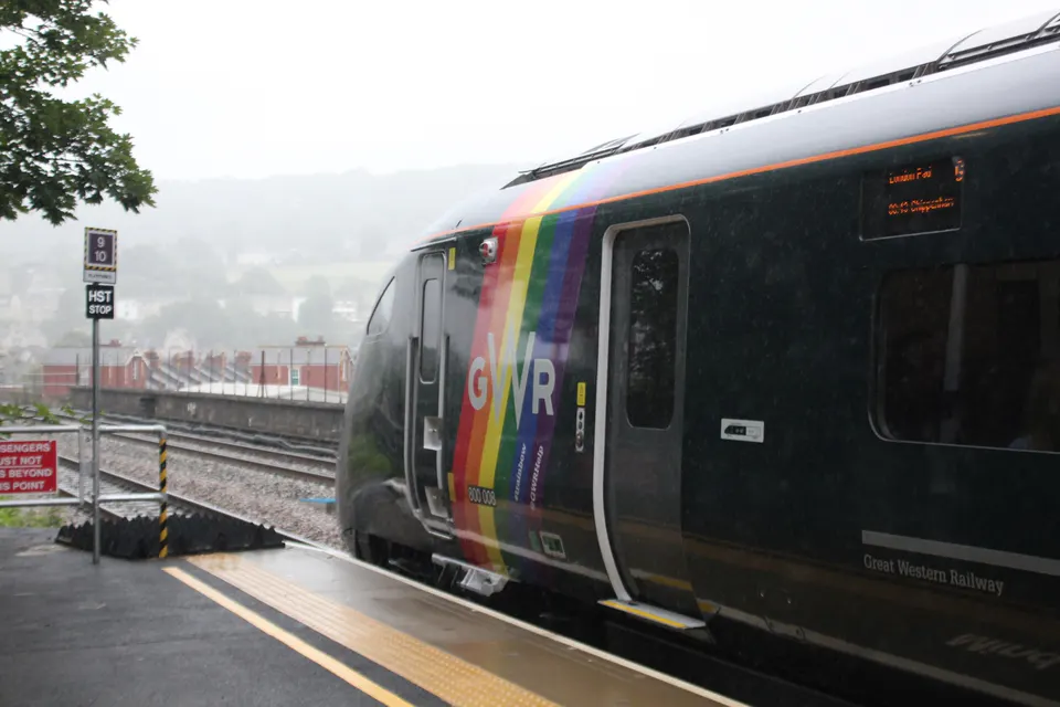 Rainbow-liveried train at Bath Spa station in the rain
