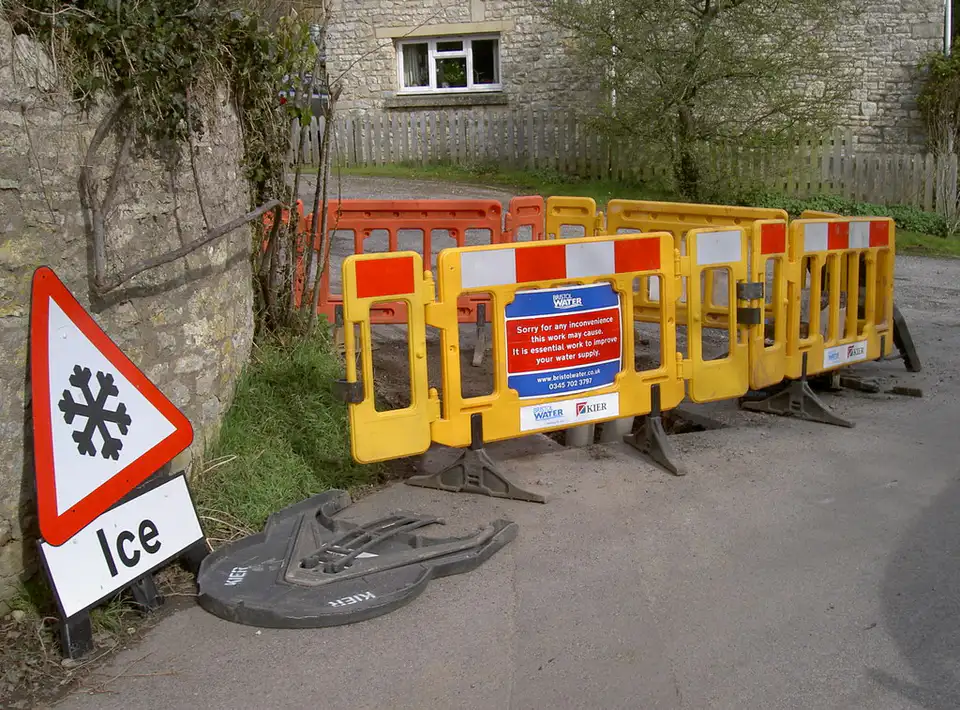 Yellow barriers and an ice warning sign by a Bath roadside
