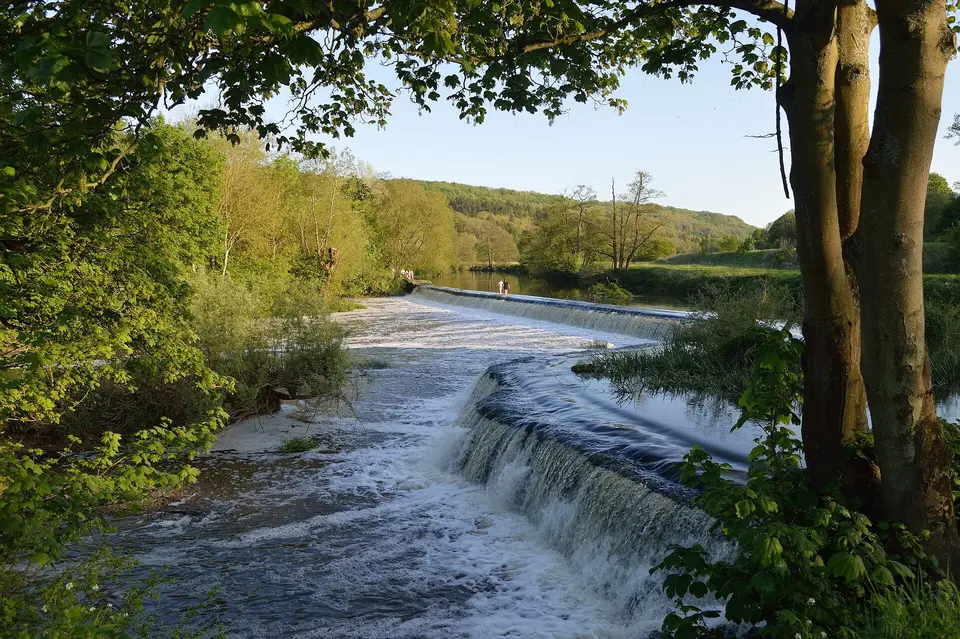 Water pouring over Warleigh Weir on the Avon, between wooded banks